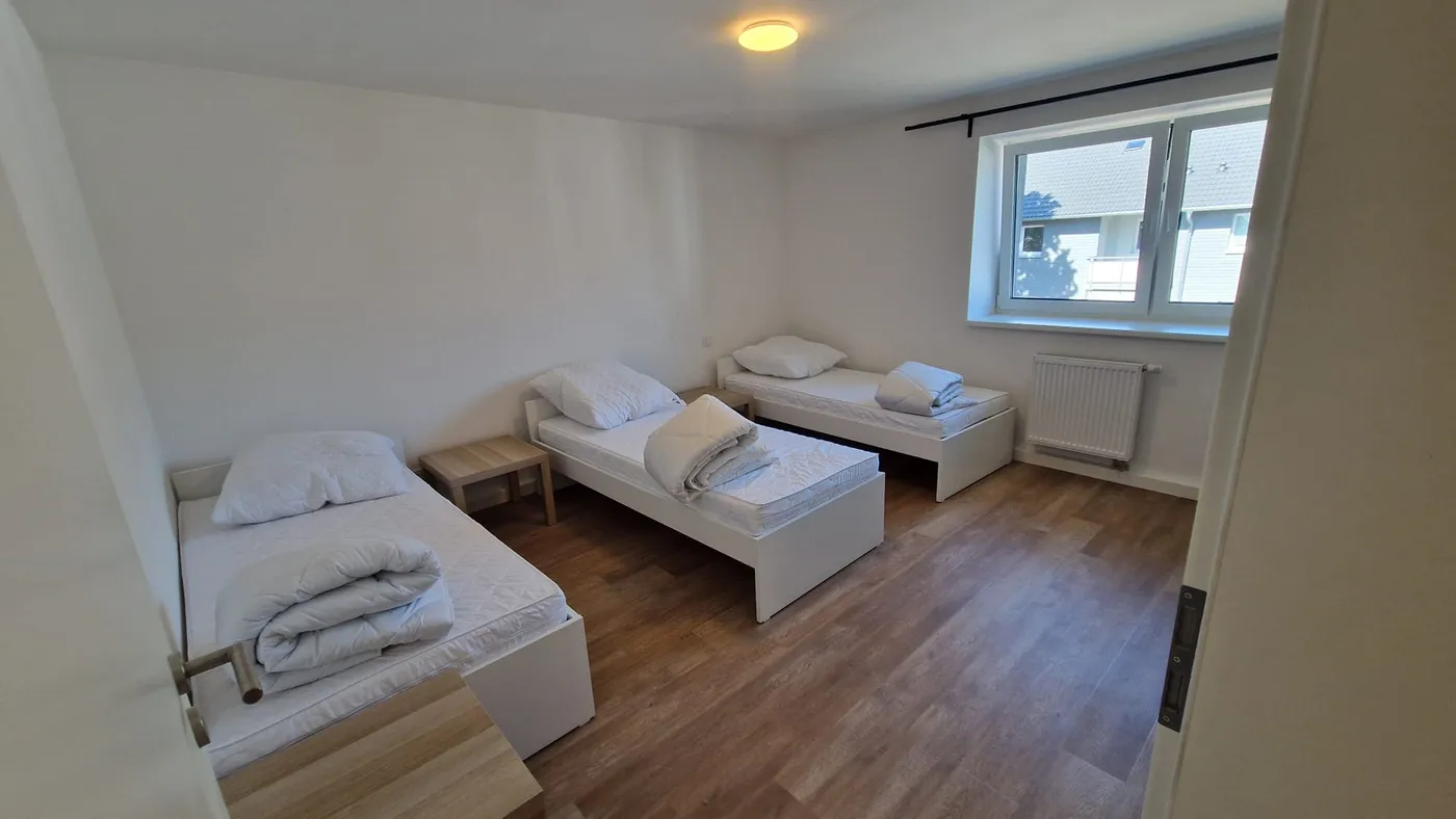 Helles, modern renoviertes Zimmer einer Monteurwohnung im Raum Landshut mit drei getrennten Einzelbetten und frischer Bettwäsche