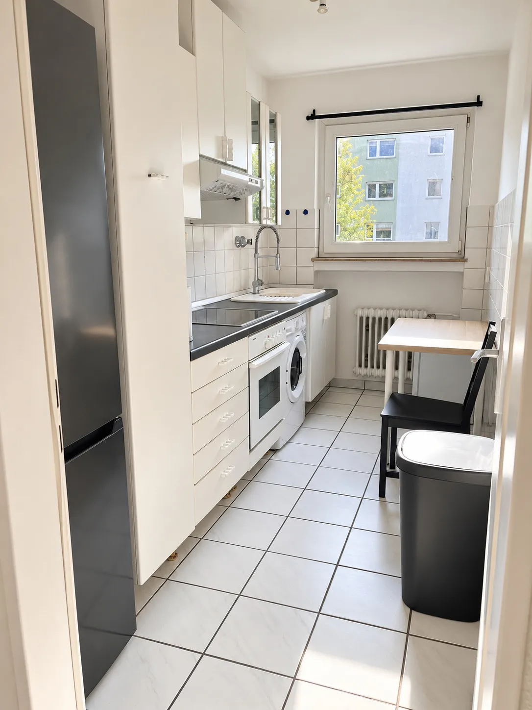 Küche mit Herd und Waschmaschine in derselben Wohnung mit hellen Zimmern und eigener Küche