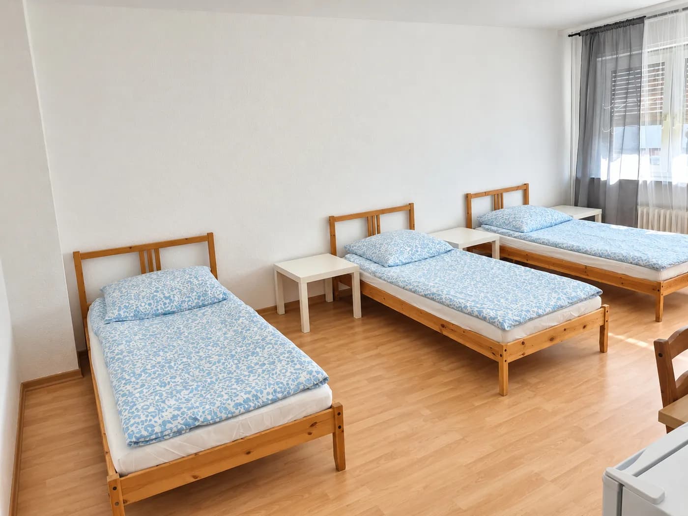 Drei Einzelbetten im Zimmer einer Wohnung mit getrennten Betten und eigener Küche