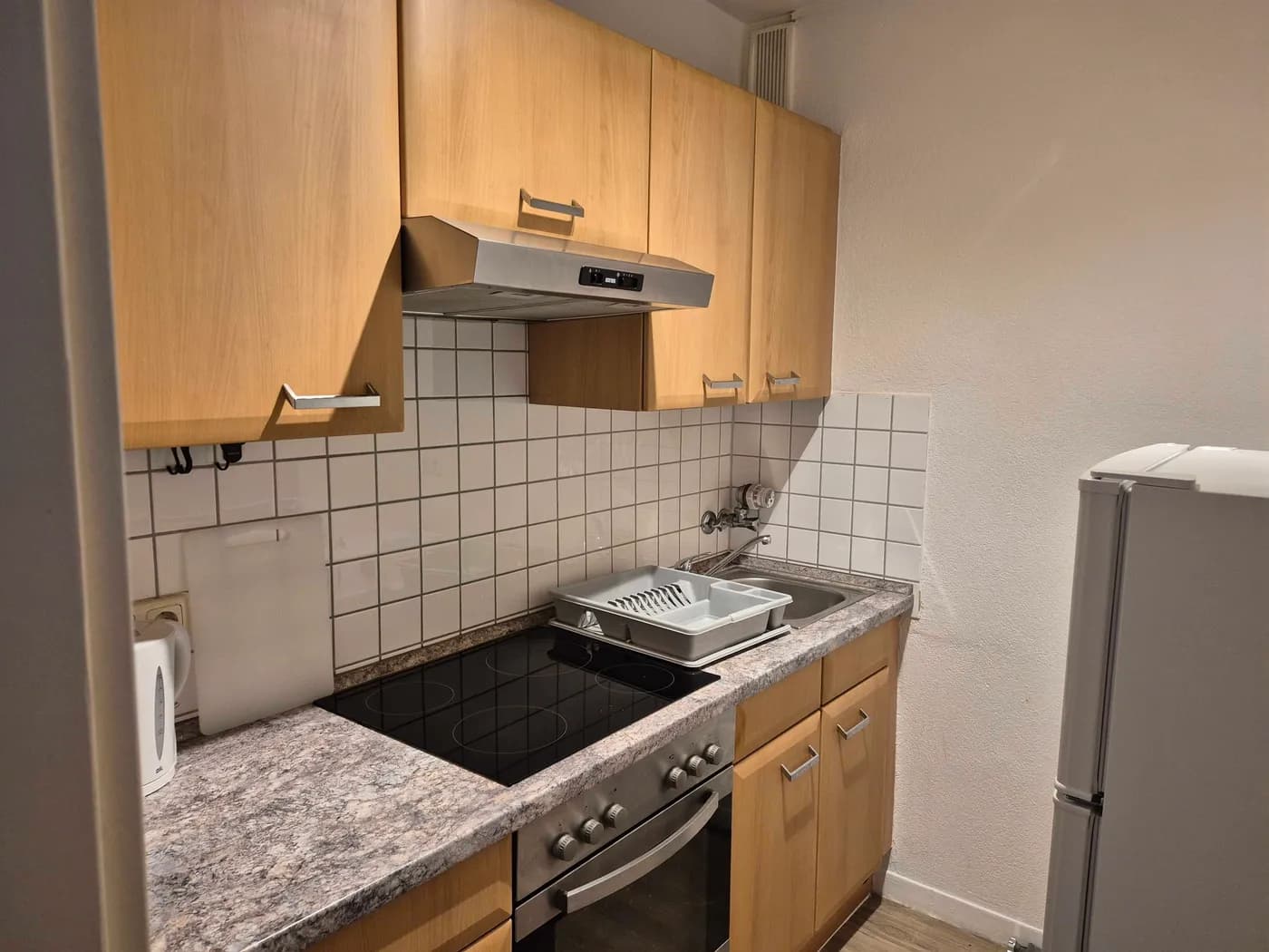Voll ausgestattete Küche mit Cerankochfeld, Backofen, Dunstabzug und Kühlschrank in einer Monteurwohnung in Offenbach