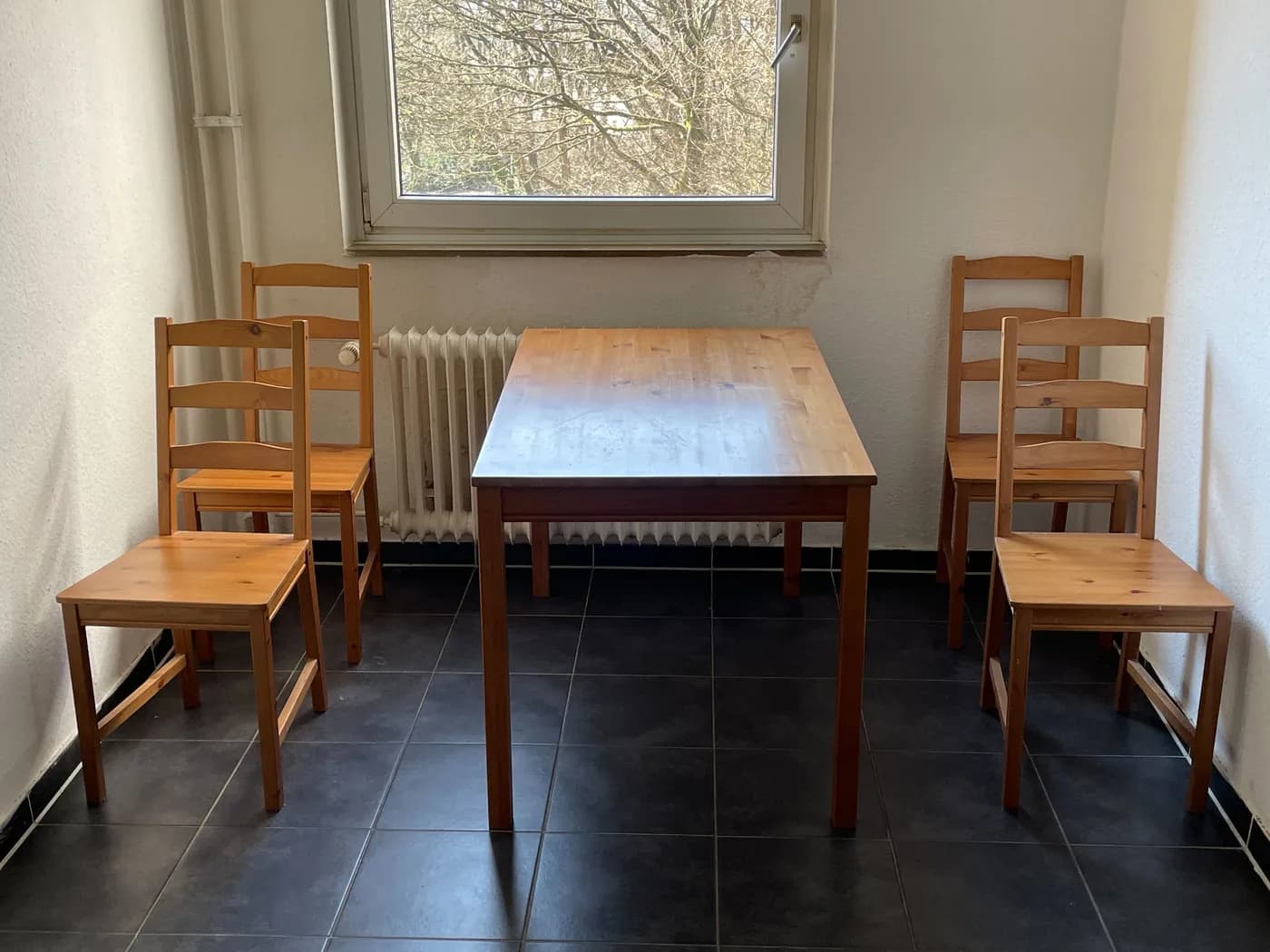 Essbereich mit Esstisch und vier Stühlen am Fenster in einer Monteurwohnung in Wesseling