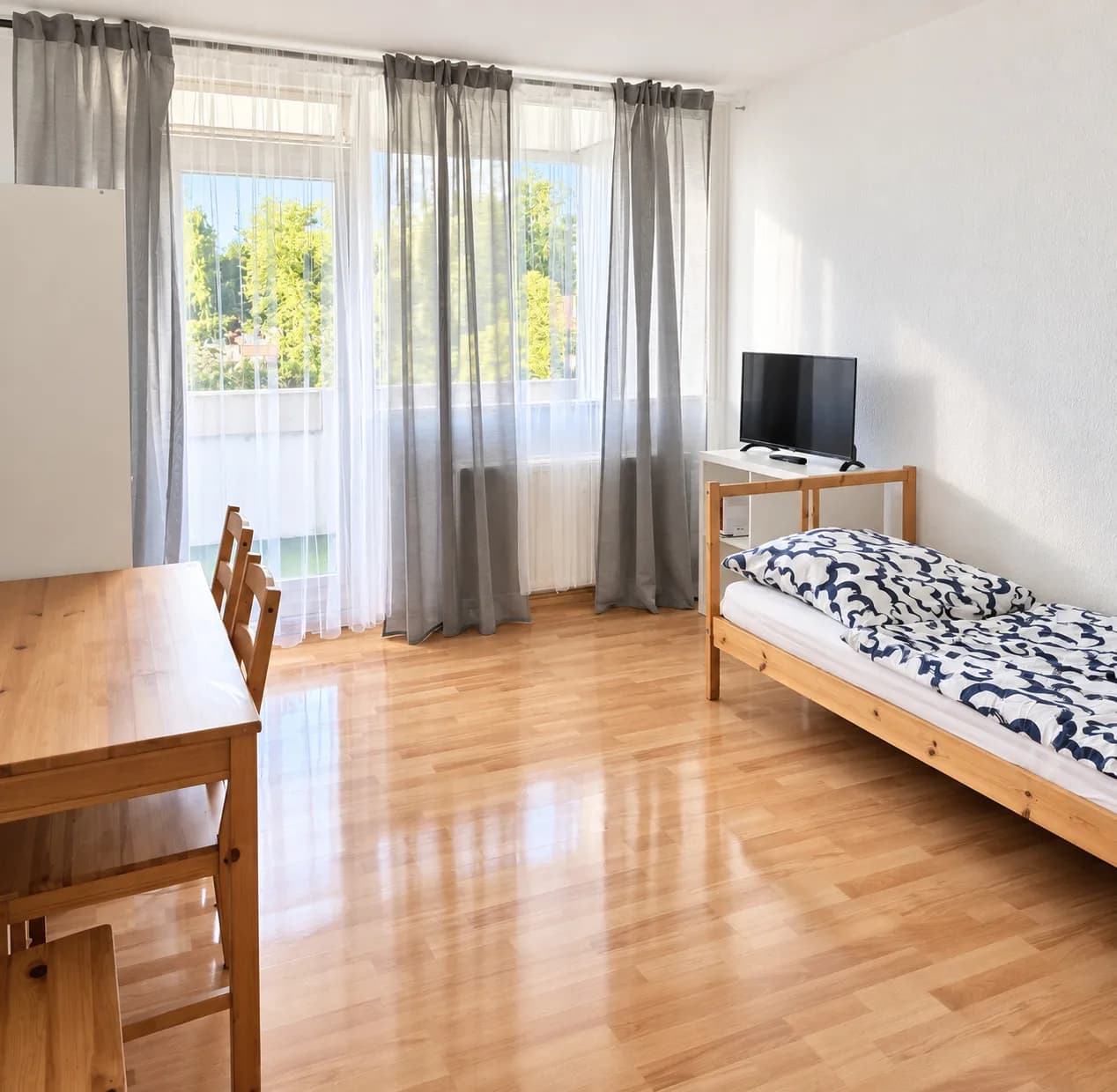 Zimmer mit Einzelbett, Tisch und Fernseher in derselben Wohnung in Bochum