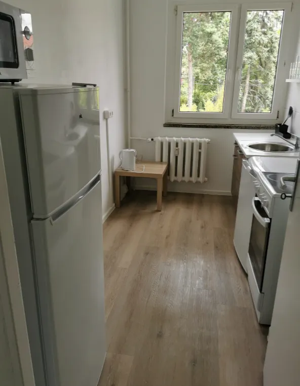 Ausgestattete Küche mit Herd, Kühlschrank und Fenster in einer Monteurwohnung in Borsdorf