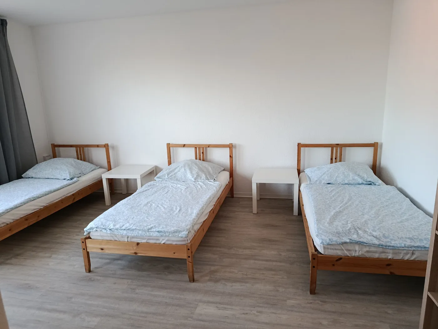 Helles Schlafzimmer einer Monteurwohnung in Dormagen mit drei getrennten Einzelbetten