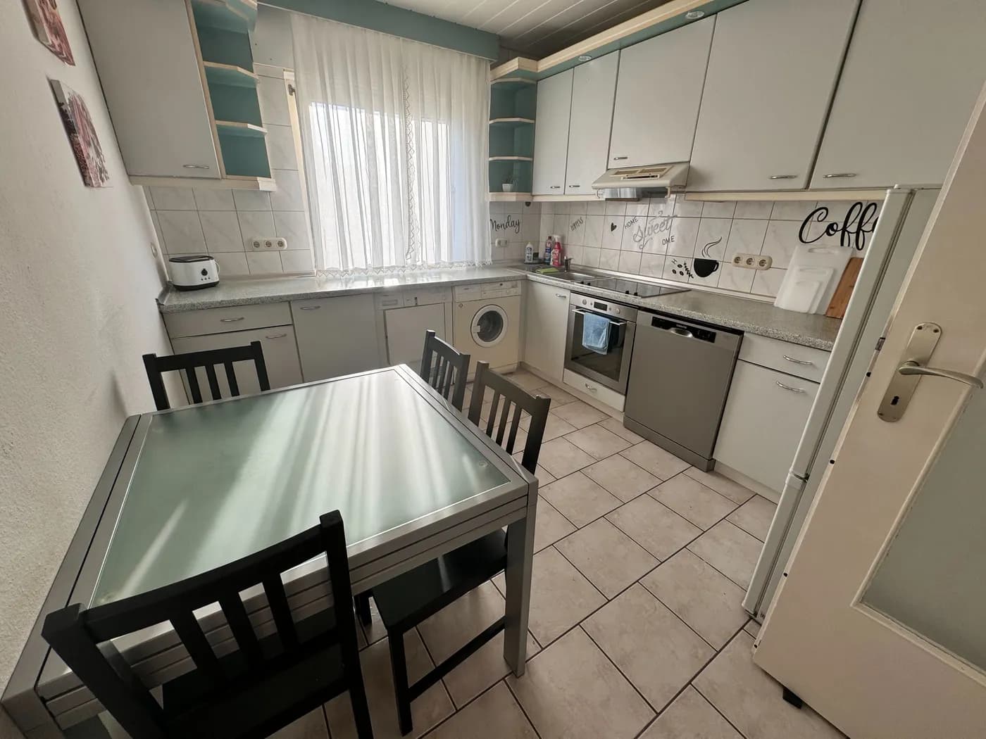 Voll ausgestattete Küche mit Cerankochfeld, Backofen, Geschirrspüler und Esstisch in einer Monteurwohnung in Dreieich