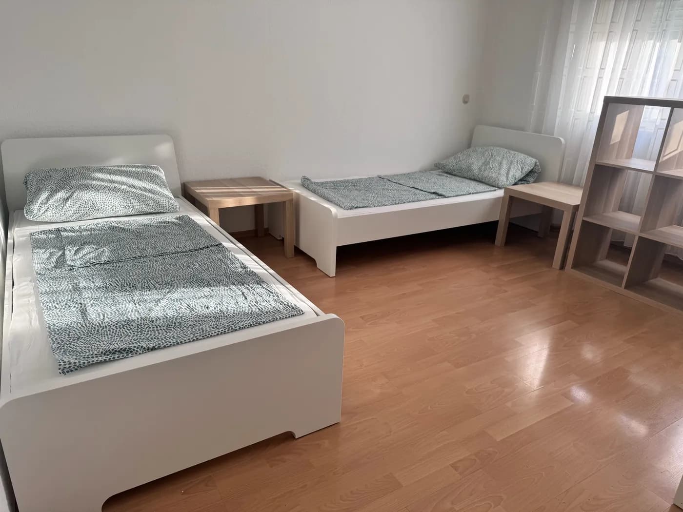 Geräumiges Zimmer der Monteurunterkunft in Dreieich mit zwei getrennten Einzelbetten und Nachttisch auf Laminatboden