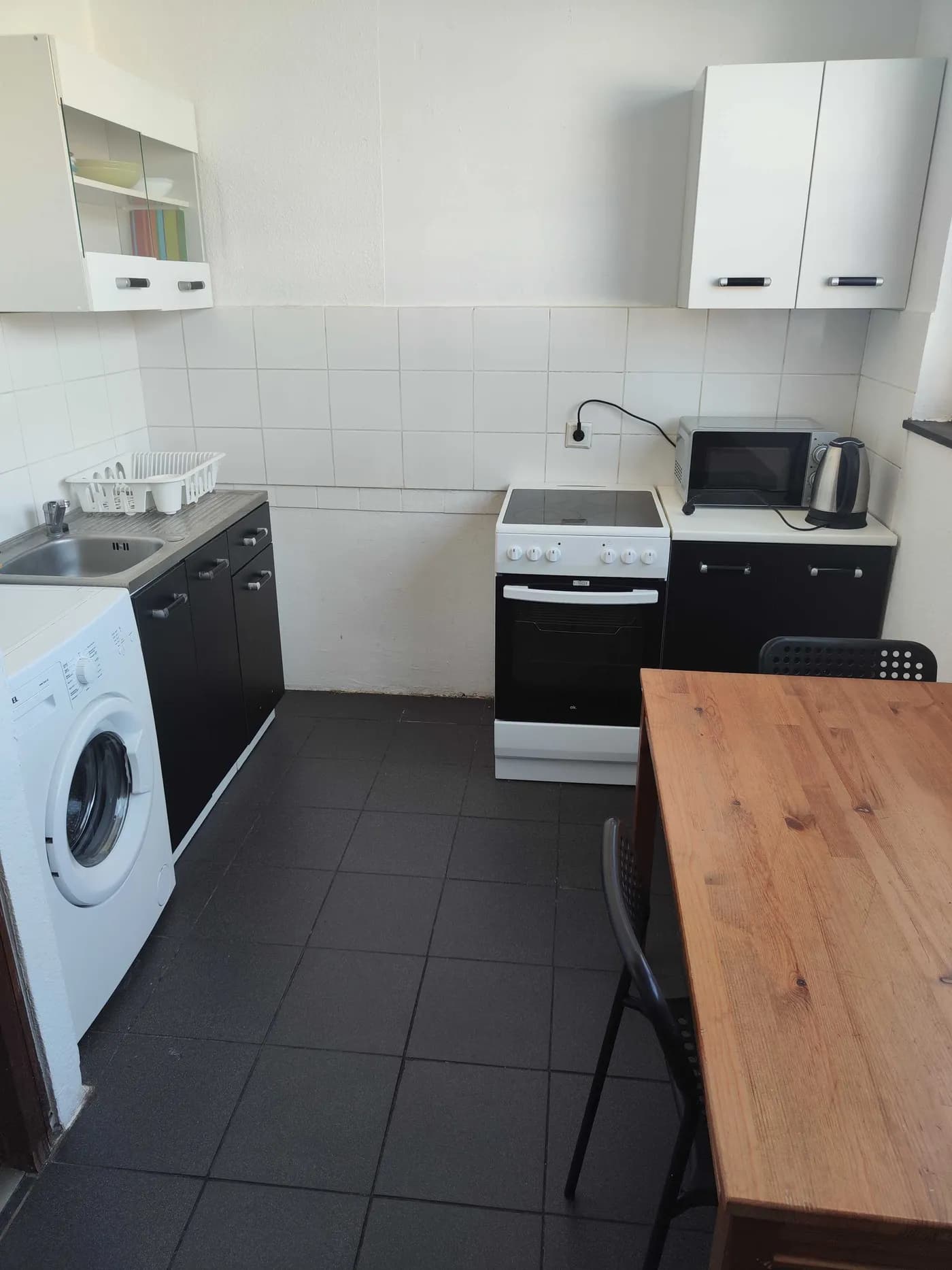 Ausgestattete Küche mit Herd, Backofen, Mikrowelle, Waschmaschine und Esstisch in einer Monteurwohnung in Erkrath