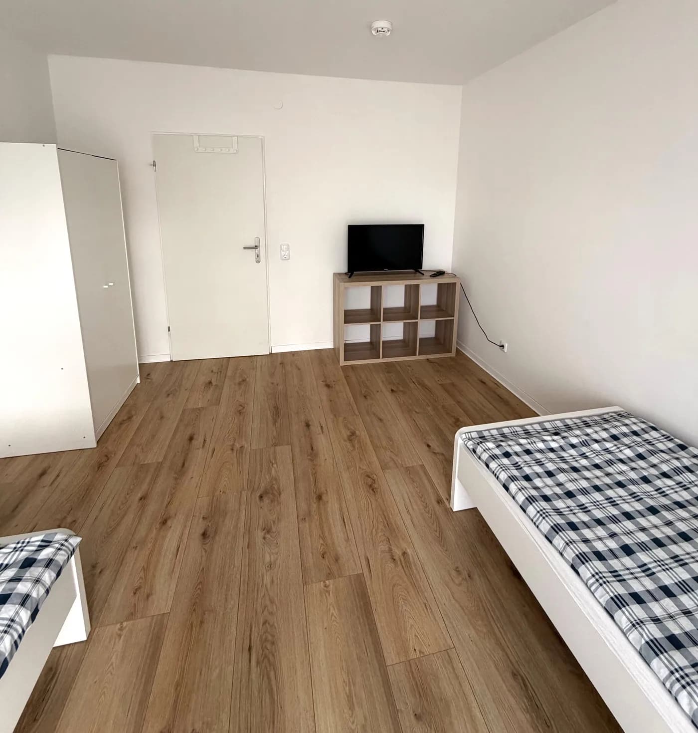 Zimmer einer Monteurwohnung in Eschweiler mit zwei getrennten Einzelbetten und Fernseher für Teams