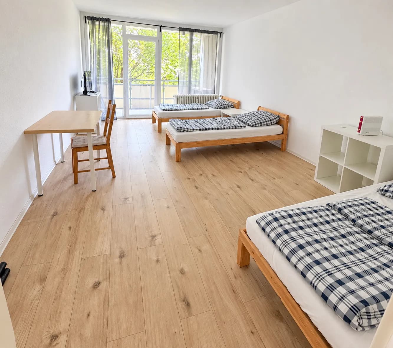 Schlafraum mit drei sichtbaren Einzelbetten und Tisch