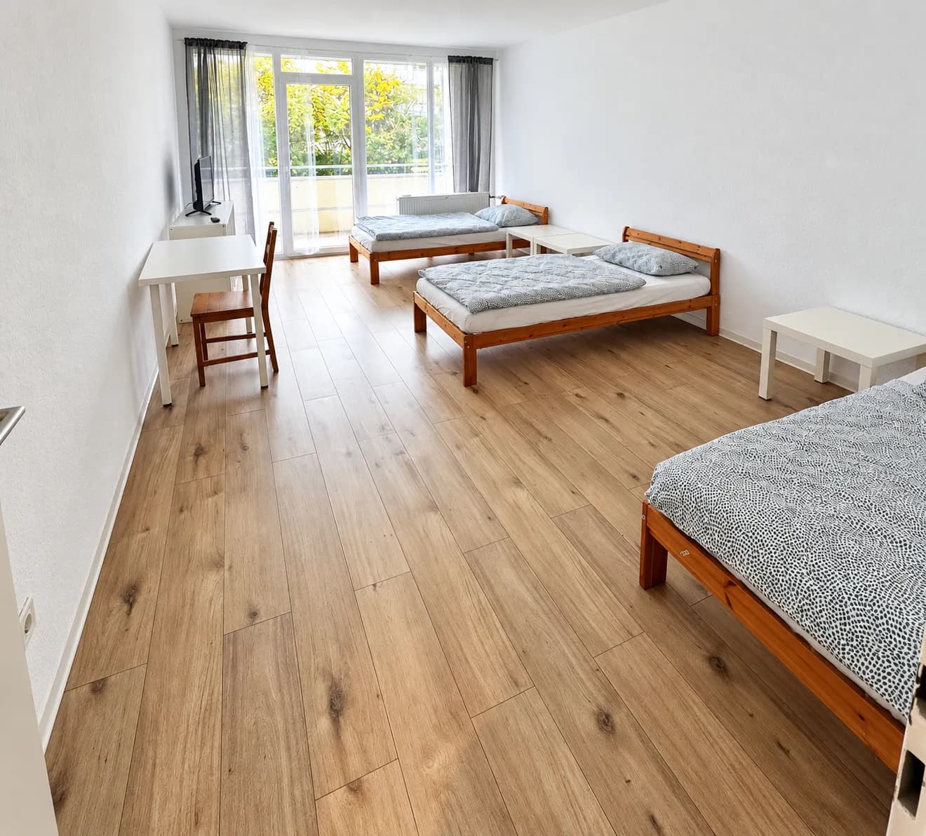 Weiterer Schlafraum mit drei sichtbaren Einzelbetten in derselben Wohnung