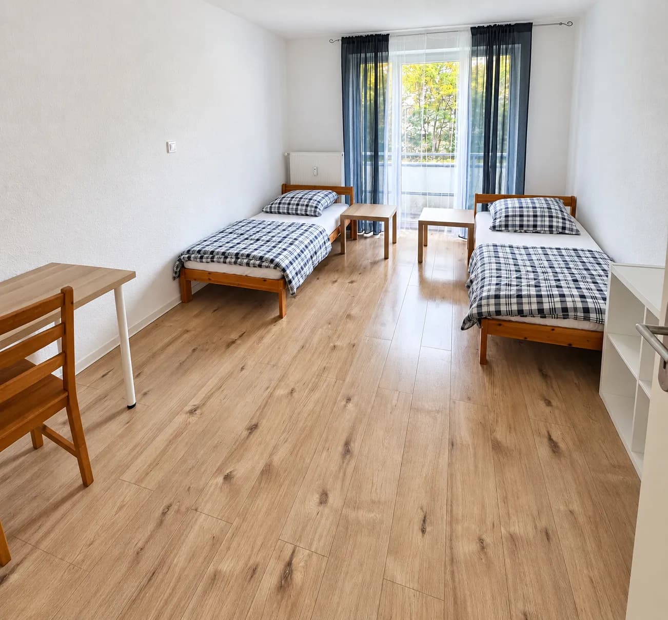 Erstes Zimmer mit zwei getrennten Einzelbetten und Tisch