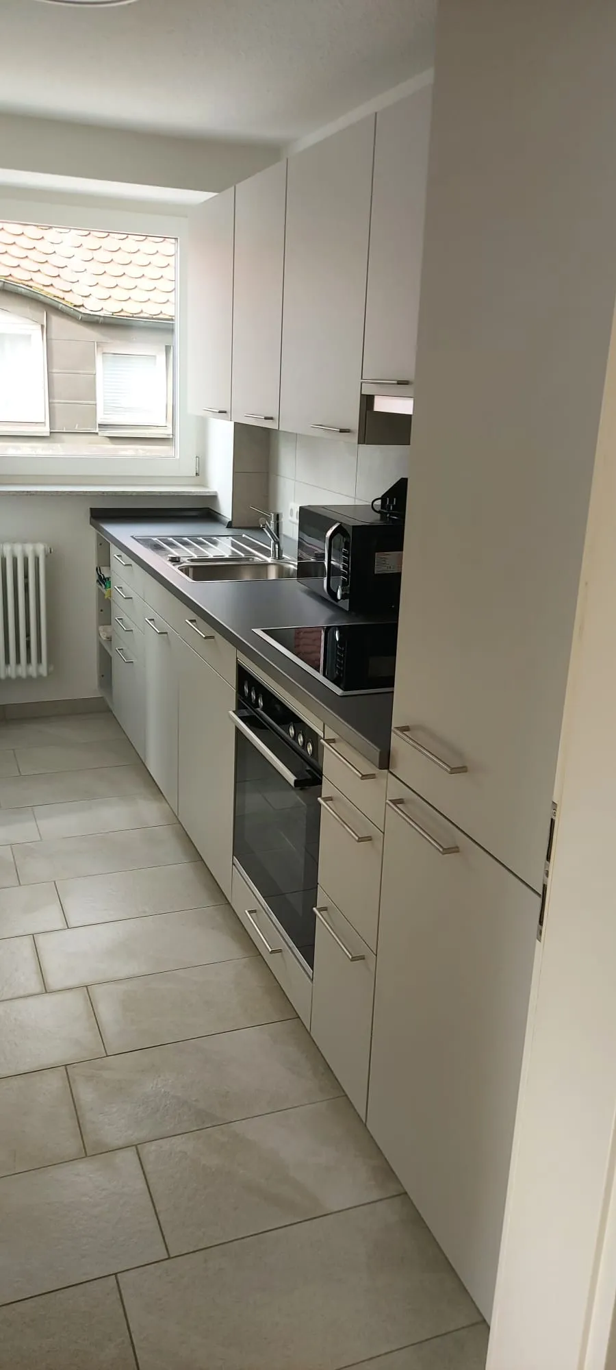 Voll ausgestattete Küche mit Herd, Backofen, Mikrowelle und Kühlschrank in einer Monteurwohnung in Friedrichshafen