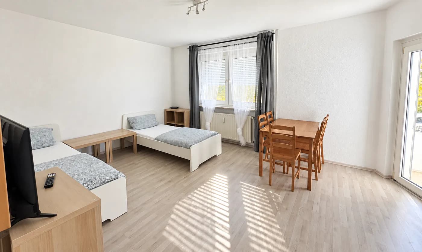 Wohnungsbeispiel: heller Schlafraum mit getrennten Betten und Tisch