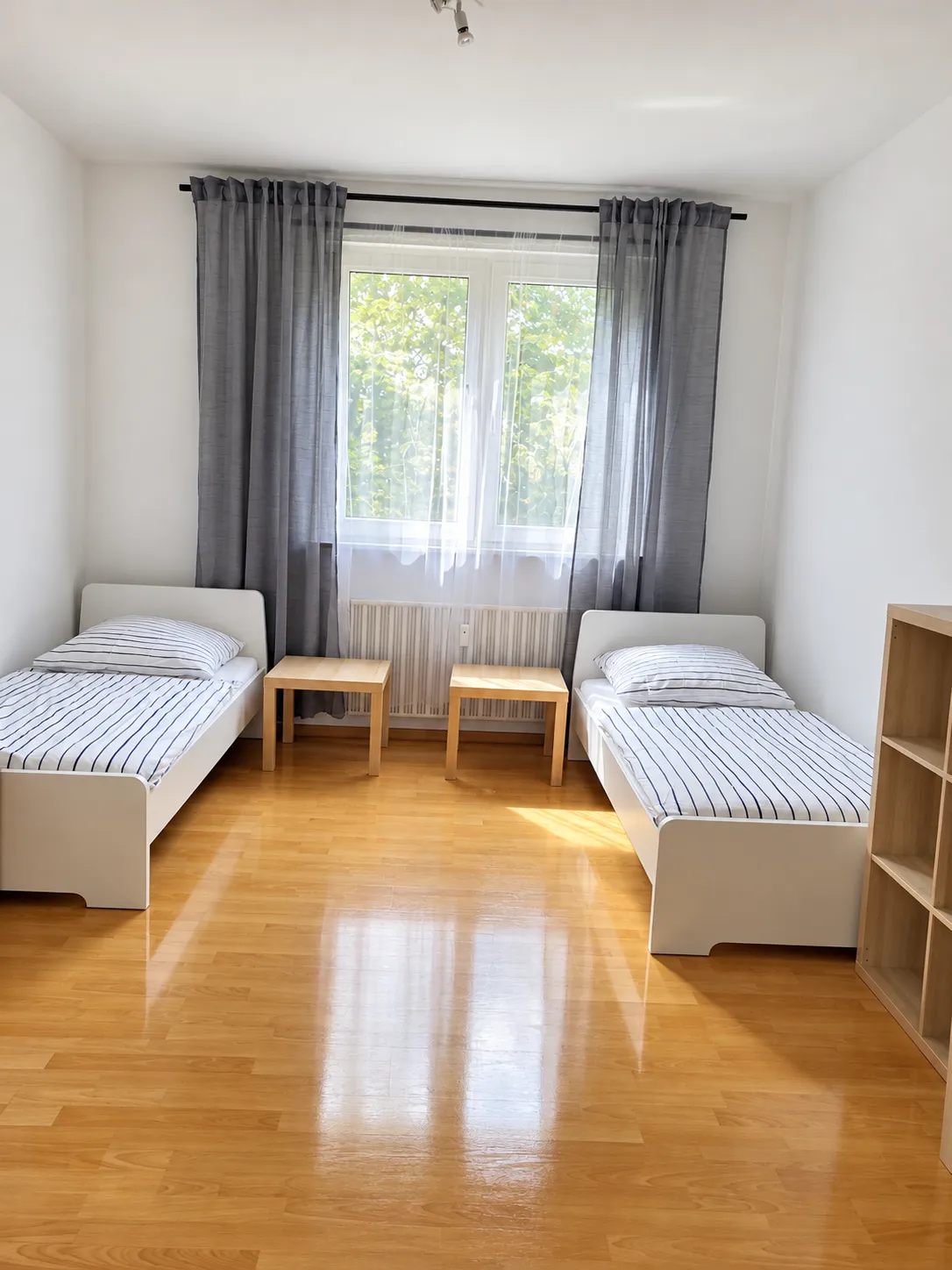 Wohnungsbeispiel: Zimmer mit getrennten Betten und Tisch am Fenster