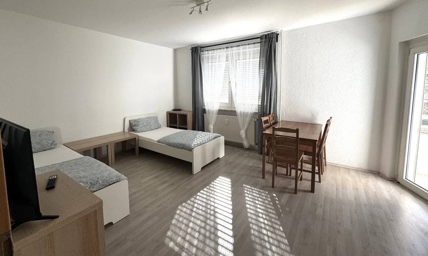 Helles Zimmer mit zwei Einzelbetten und Esstisch in einem Monteurzimmer in Gelsenkirchen