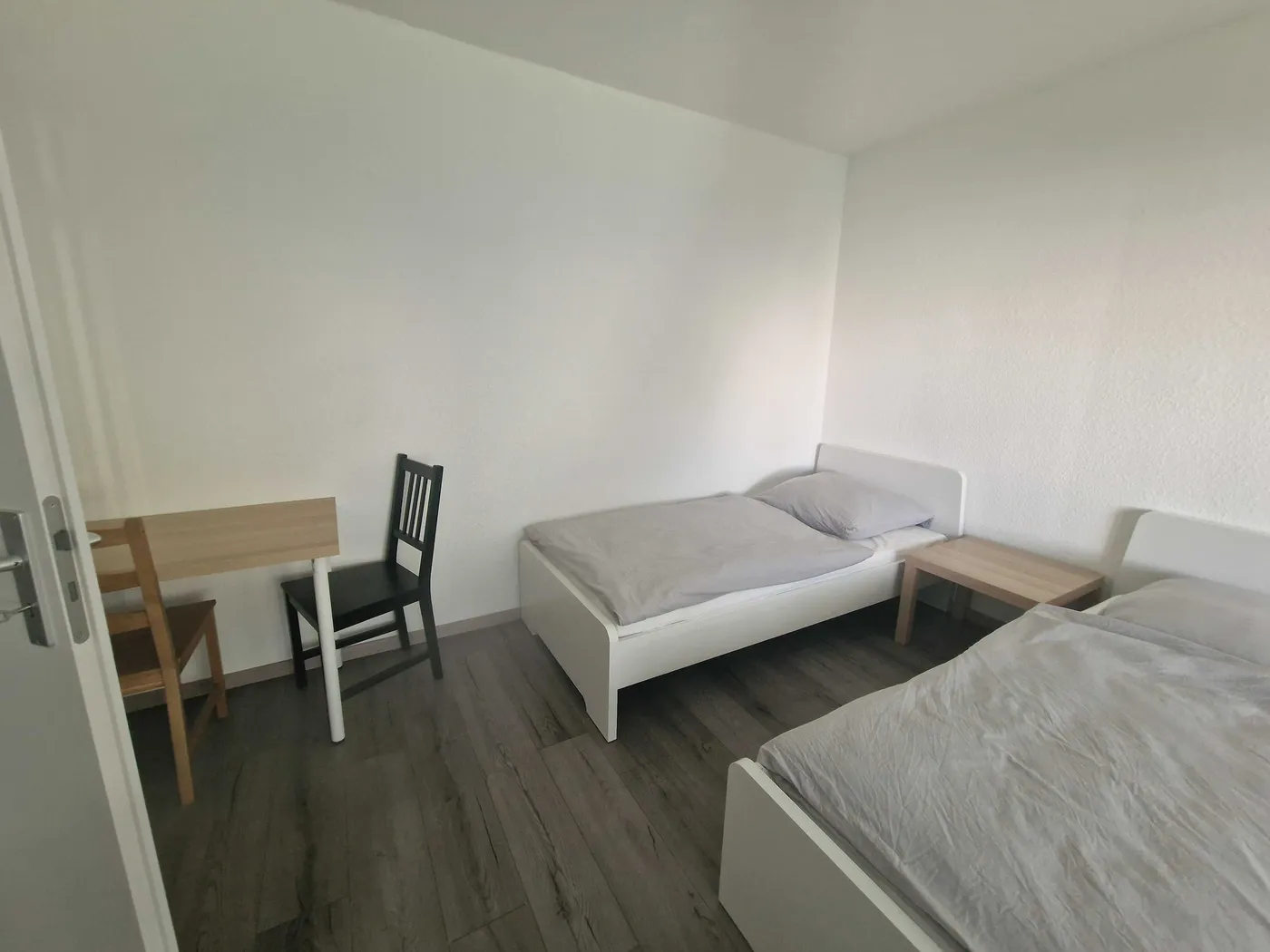 Helles Schlafzimmer einer Monteurwohnung in Hagen mit zwei getrennten Einzelbetten und Arbeitsplatz