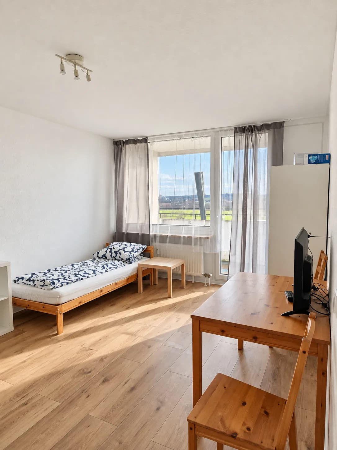 Zimmer mit Einzelbett, Tisch und Fernseher in einer Hometime24 Wohnung in Bochum-Querenburg