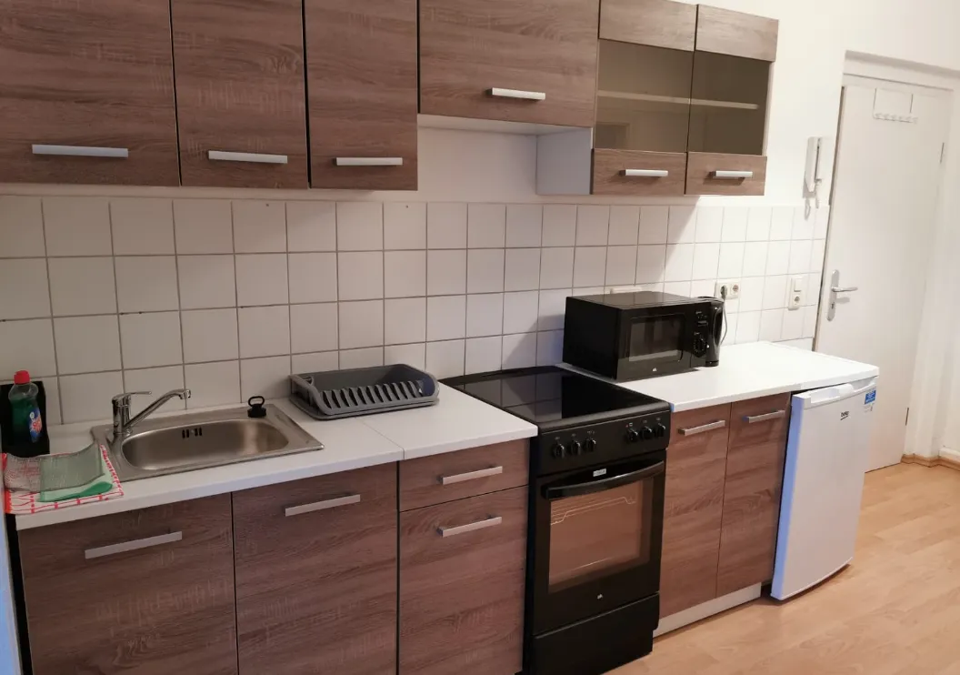 Voll ausgestattete Küche mit Herd, Backofen, Mikrowelle und Kühlschrank in einer Monteurwohnung in Heidenau