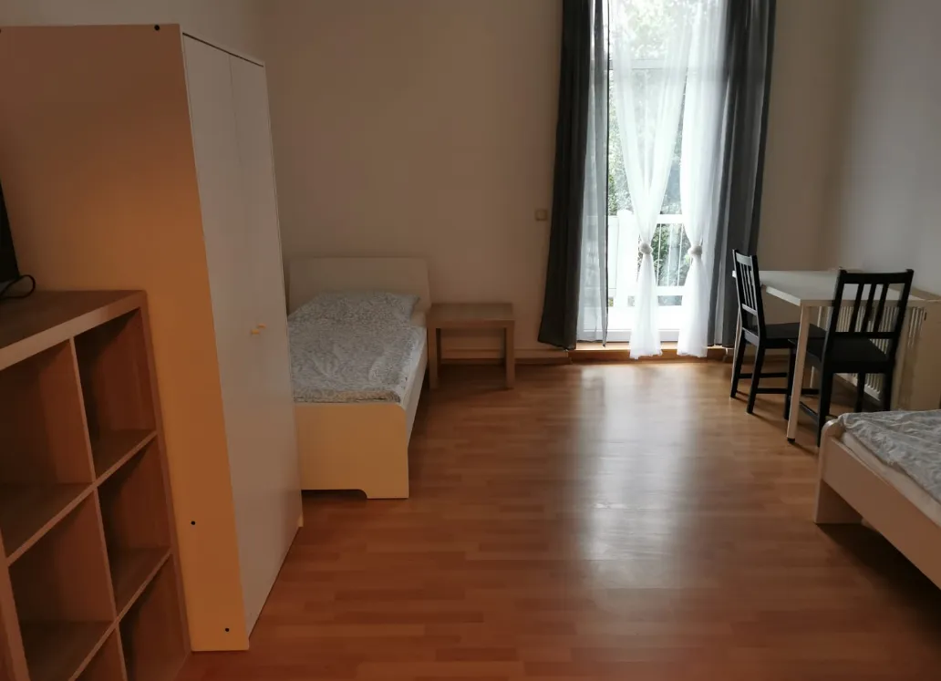 Weiteres sonniges Zimmer der Monteurunterkunft in Heidenau mit zwei Einzelbetten, Balkontür und Regal