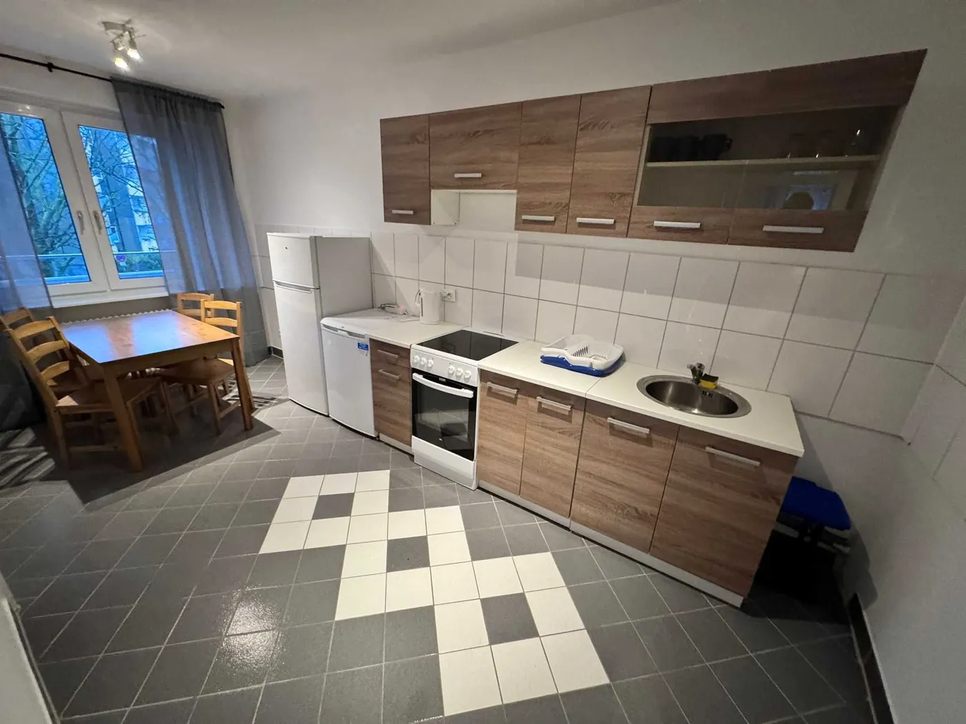 Moderne, voll ausgestattete Küche mit Herd, Backofen, Kühlschrank und Esstisch in einer Monteurwohnung in Hürth