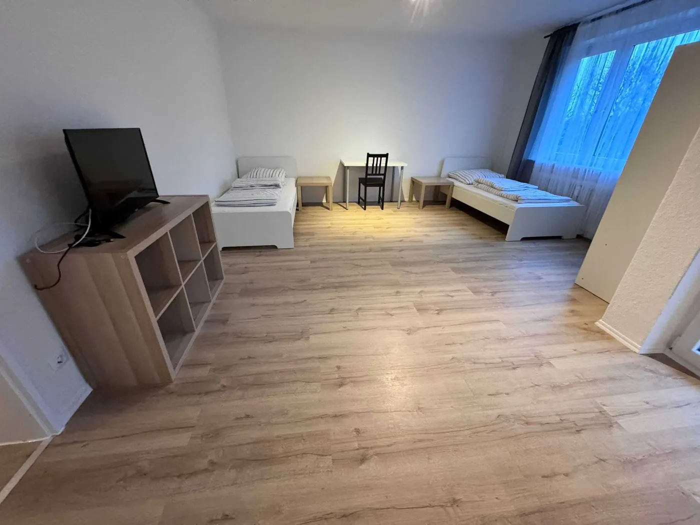 Weiteres geräumiges Zimmer der Monteurunterkunft in Hürth mit zwei Einzelbetten, Sitzgelegenheit und Flachbildfernseher