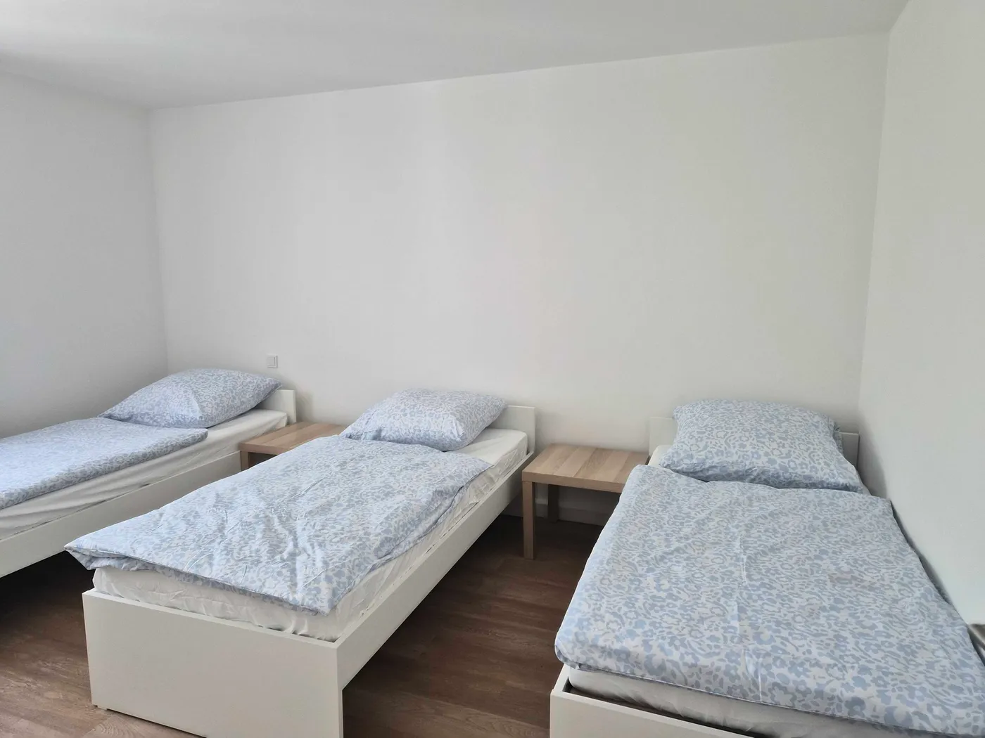 Schlafzimmer mit drei getrennten Einzelbetten in einer Hometime24 Wohnung in Kösching