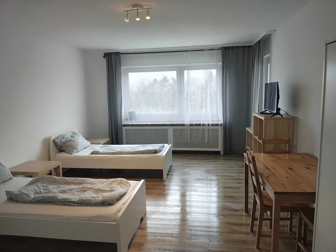 Helles Schlafzimmer einer Monteurwohnung in Krefeld mit zwei getrennten Einzelbetten und Essplatz