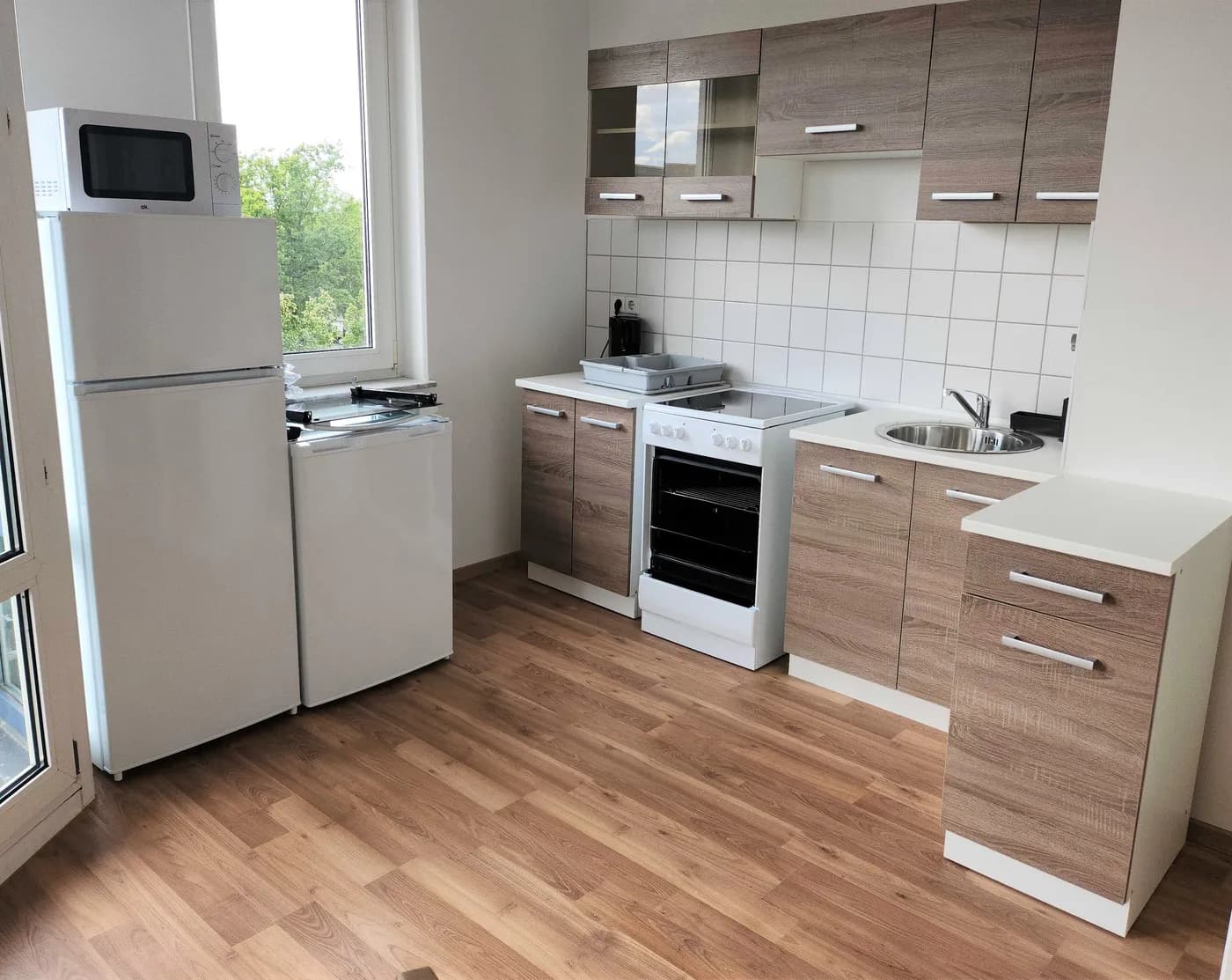 Voll ausgestattete Küche mit Herd, Backofen, Kühlschrank und Esstisch in einer Monteurwohnung in Leipzig