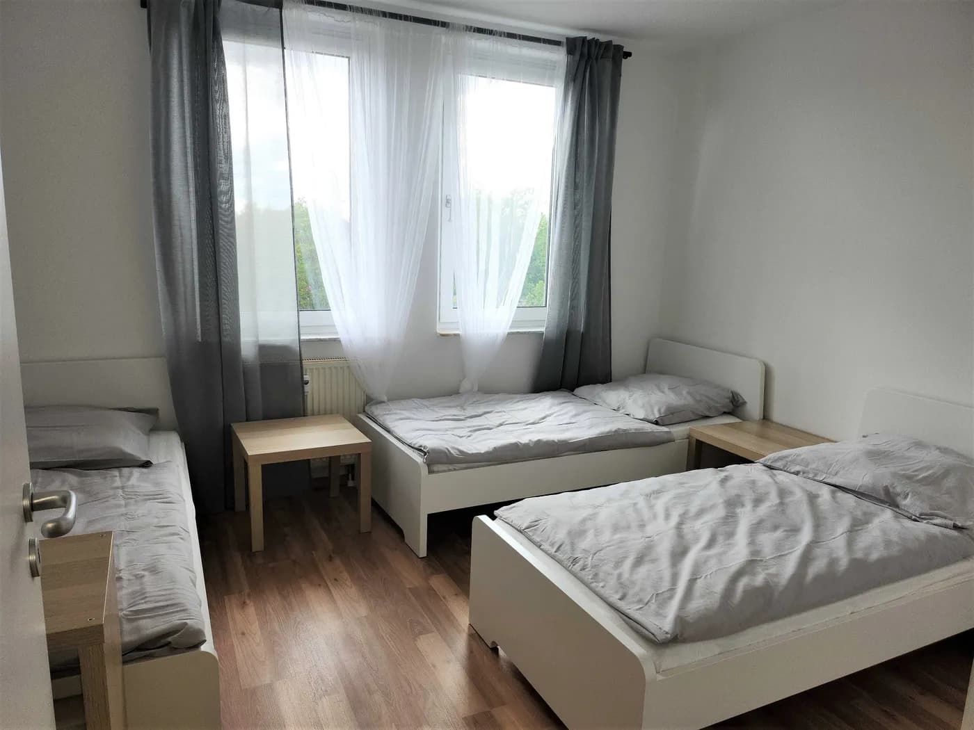 Geräumiges Zimmer der Monteurunterkunft in Leipzig mit drei getrennten Einzelbetten und großem Fenster