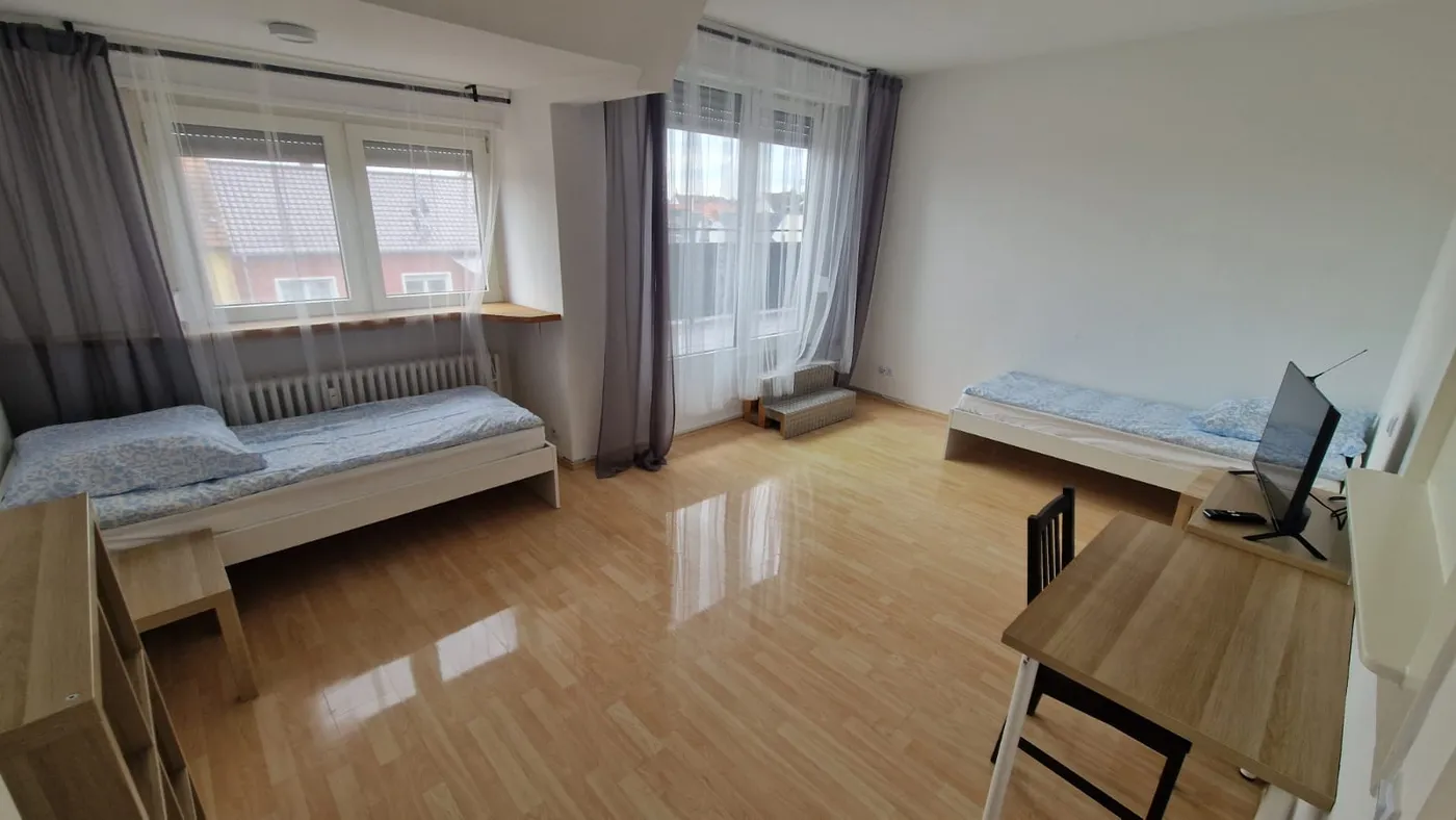 Helles Schlafzimmer einer Monteurwohnung in Ludwigshafen mit zwei getrennten Einzelbetten und Arbeitsplatz