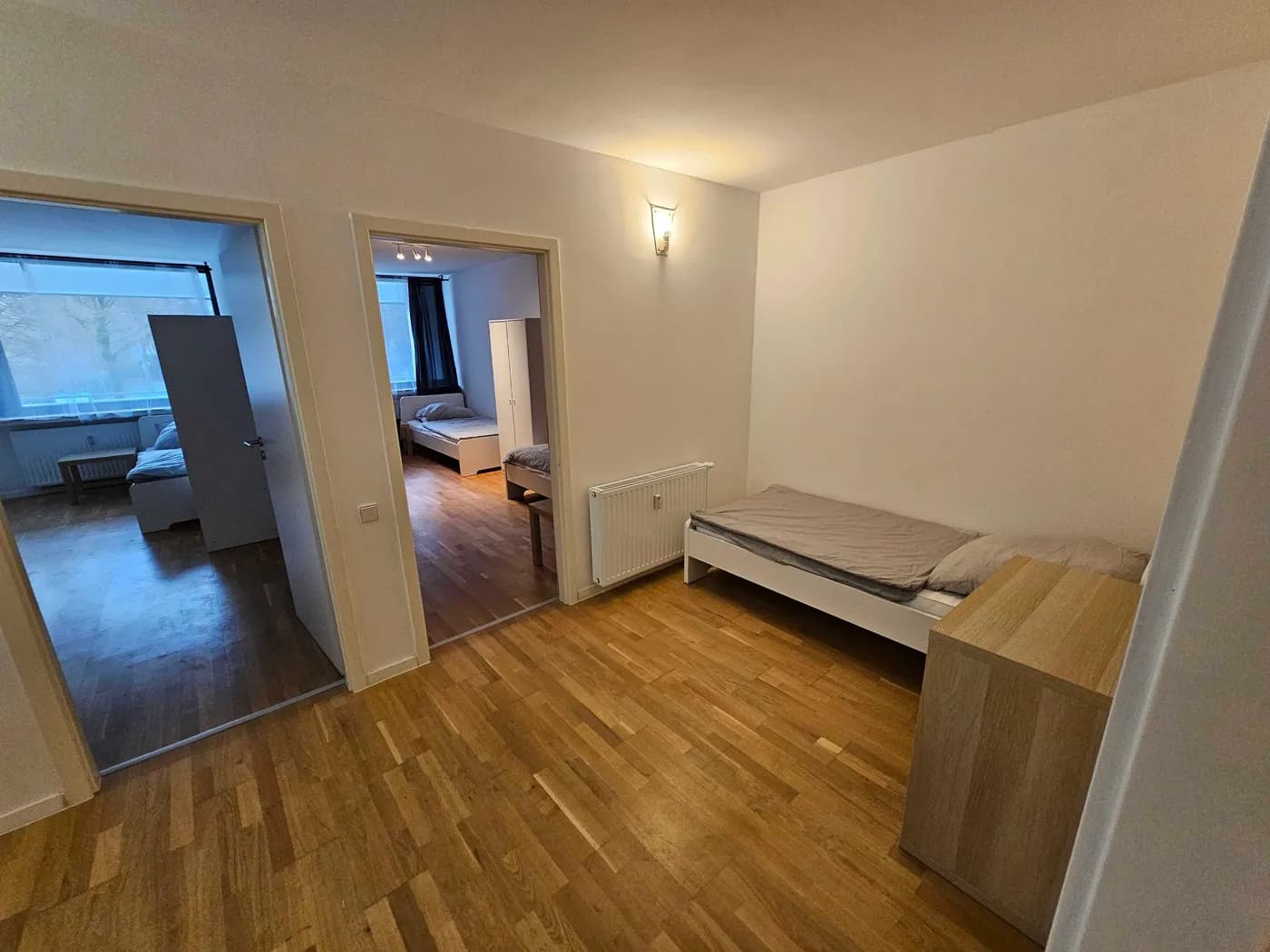 Helles Schlafzimmer einer Monteurwohnung in Ratingen mit Einzelbett und Durchblick in weitere Zimmer