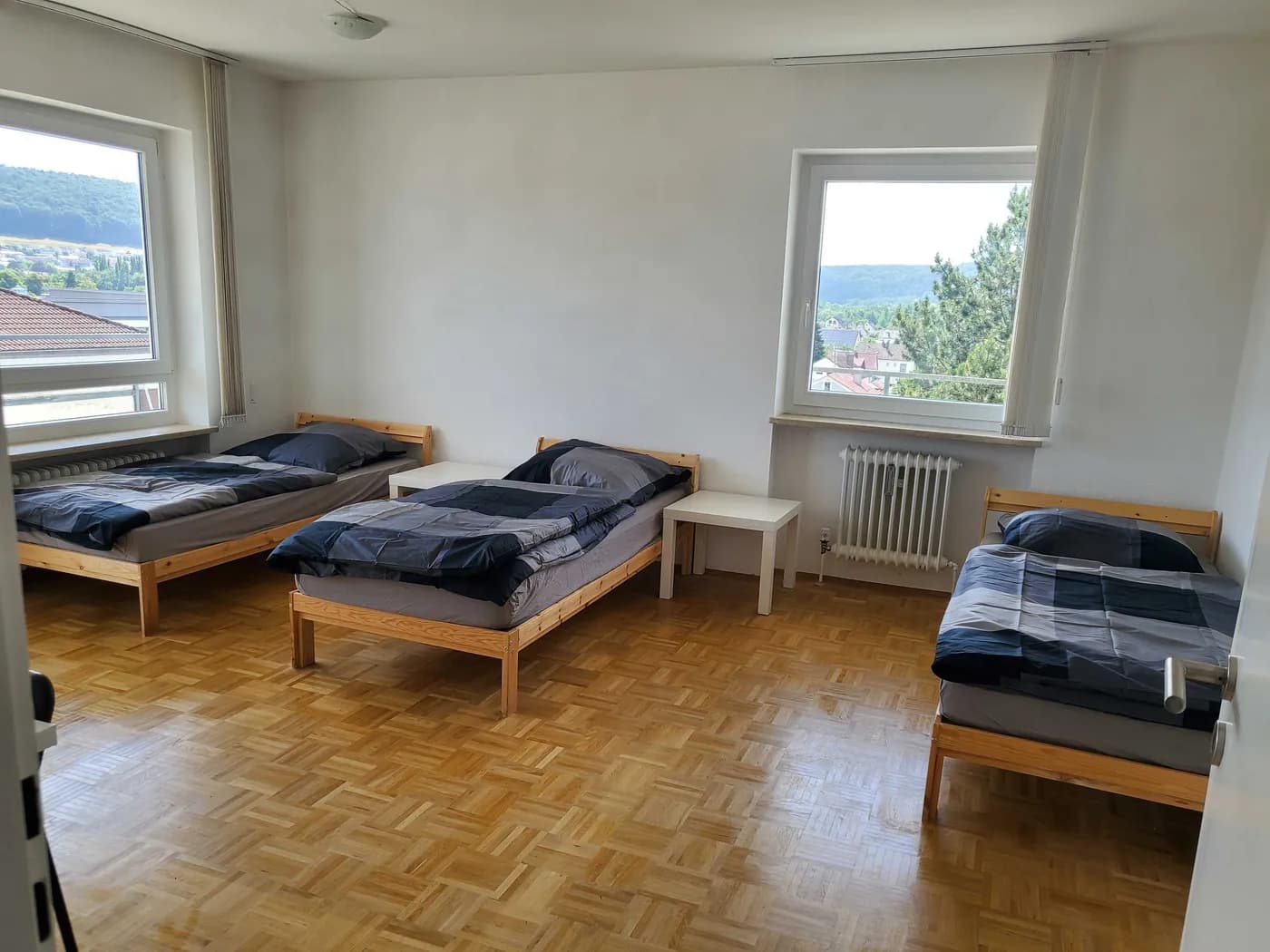 Helles Schlafzimmer einer Monteurwohnung in Kelheim bei Regensburg mit drei Einzelbetten und Aussicht