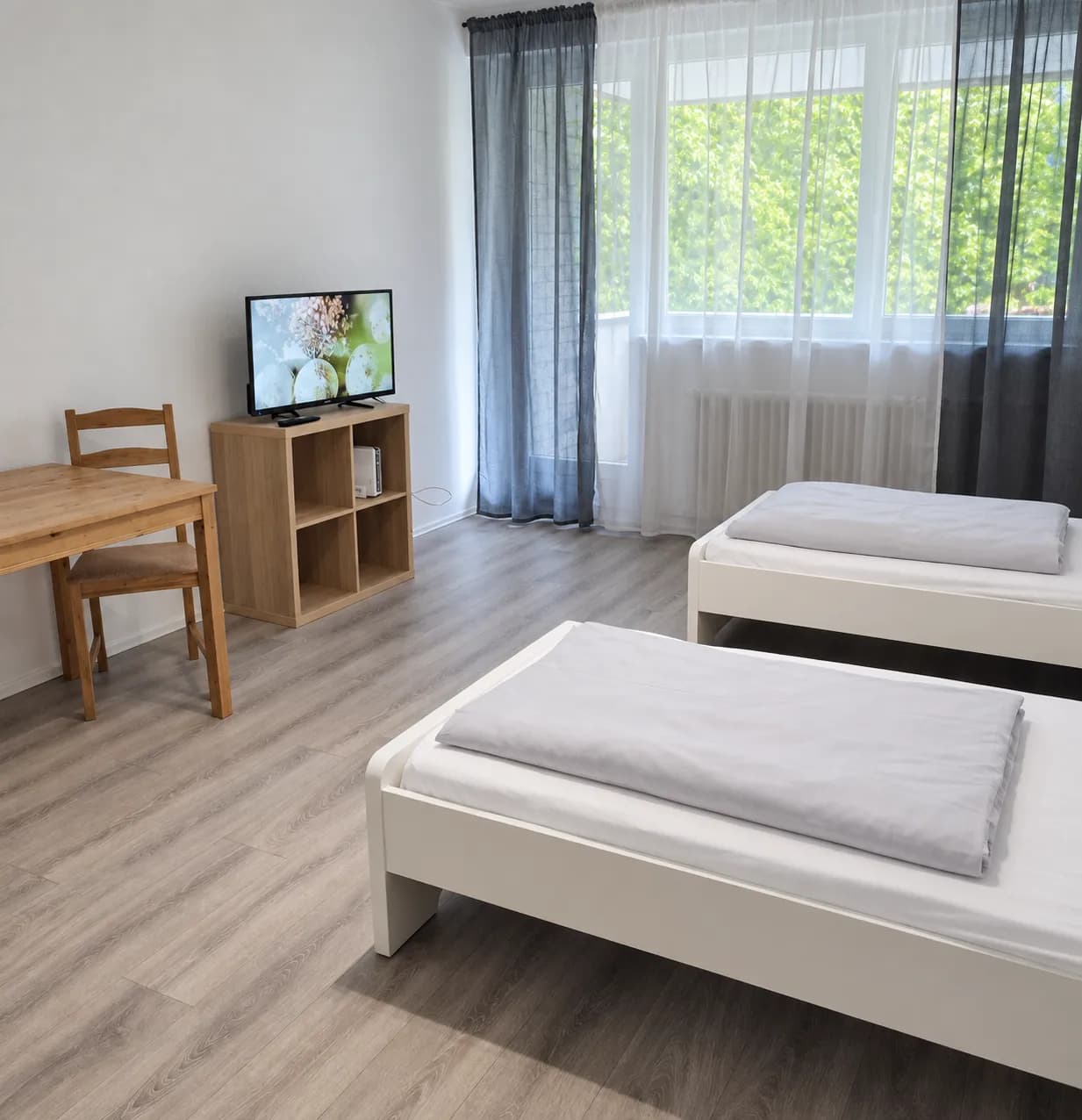 Zimmer mit zwei getrennten Einzelbetten und Esstisch in einer Hometime24 Wohnung in Solingen-Mitte