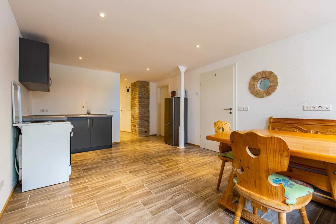 Küchen- und Essbereich mit Herd, Kühlschrank und großem Holztisch in einer Monteurwohnung in Weingarten