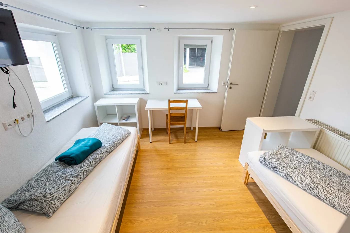 Helles Schlafzimmer einer Monteurwohnung in Weingarten mit zwei getrennten Einzelbetten, Schreibtisch und Wandfernseher