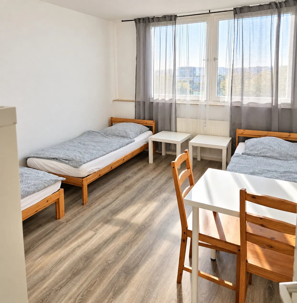Zimmer mit drei Einzelbetten und Esstisch in einer Hometime24 Wohnung in Bochum-Querenburg